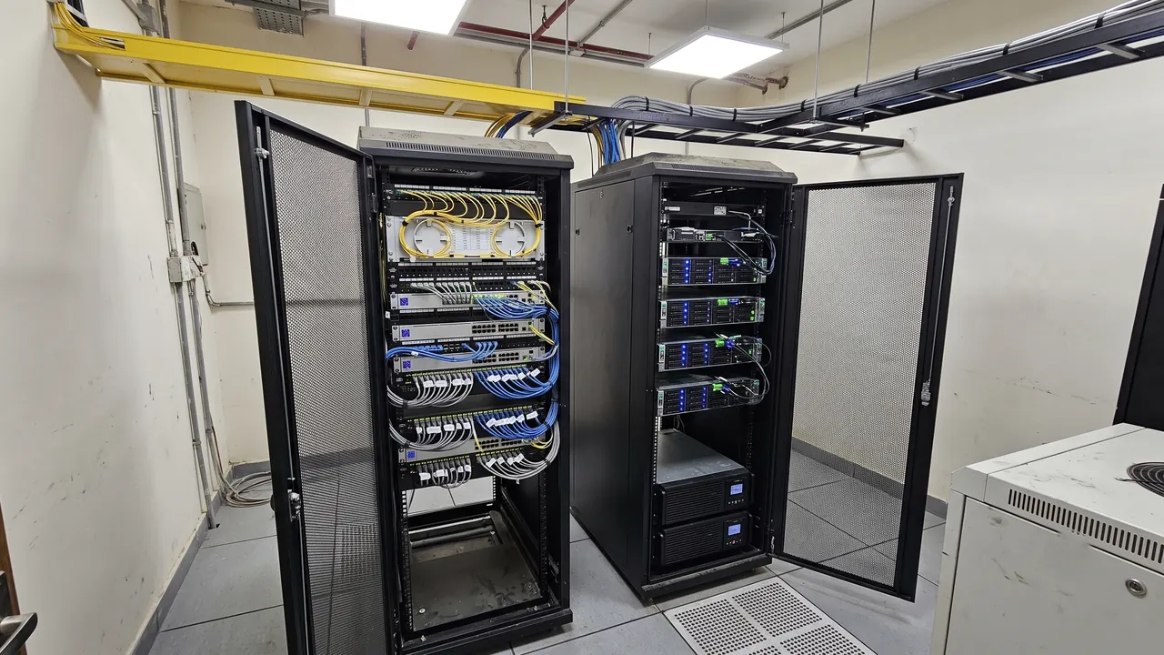 Two server racks with labelled fiber and Cat6 patching under an overhead fiber runner