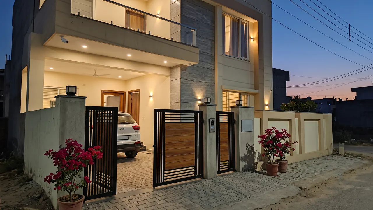 Two-storey villa at dusk with discreet turret cameras under the balcony and on the gate pillar, no visible wiring